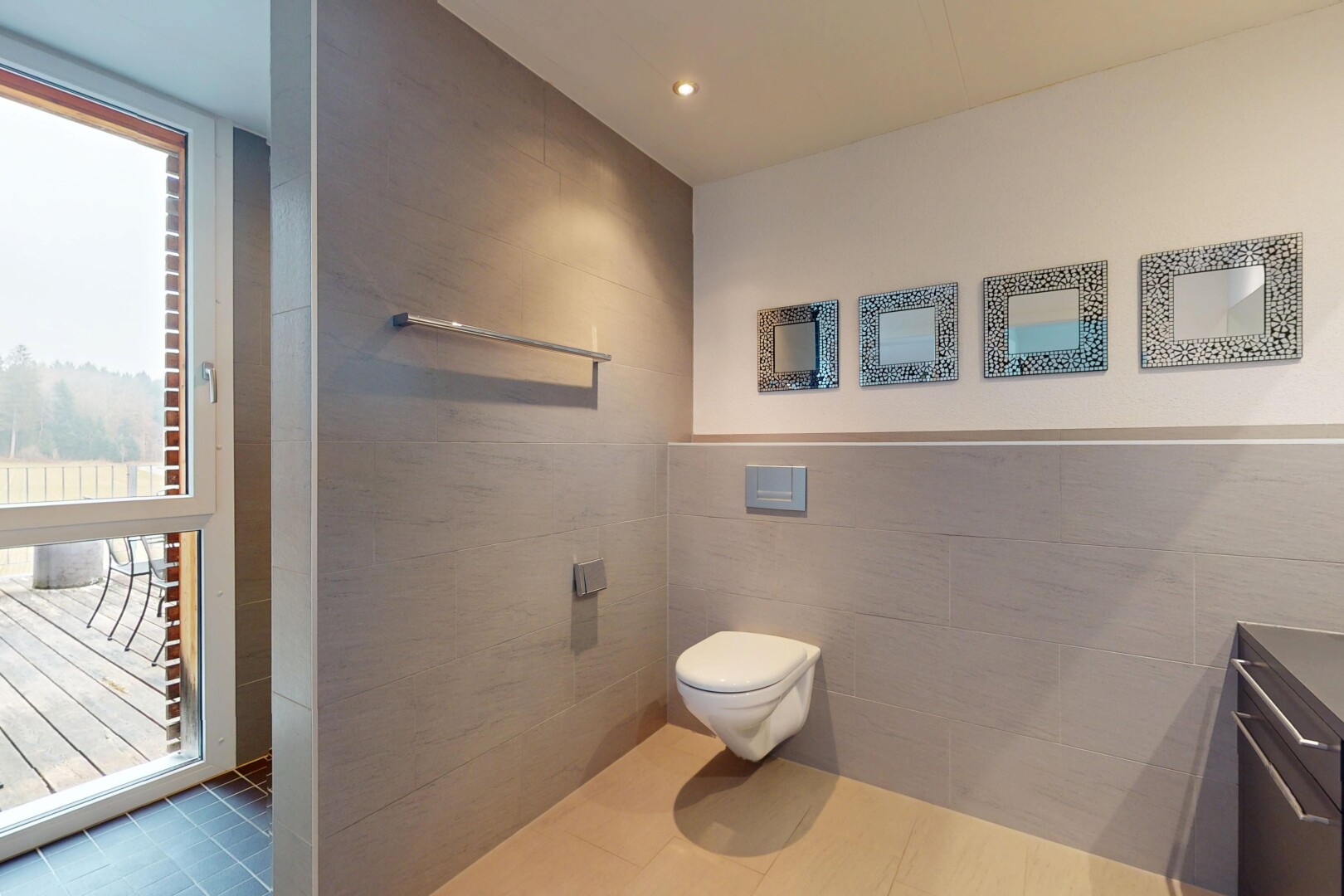 salle de bains avec toilettes, meuble-lavabo, lumière naturelle, carrelage, et mur carrelé