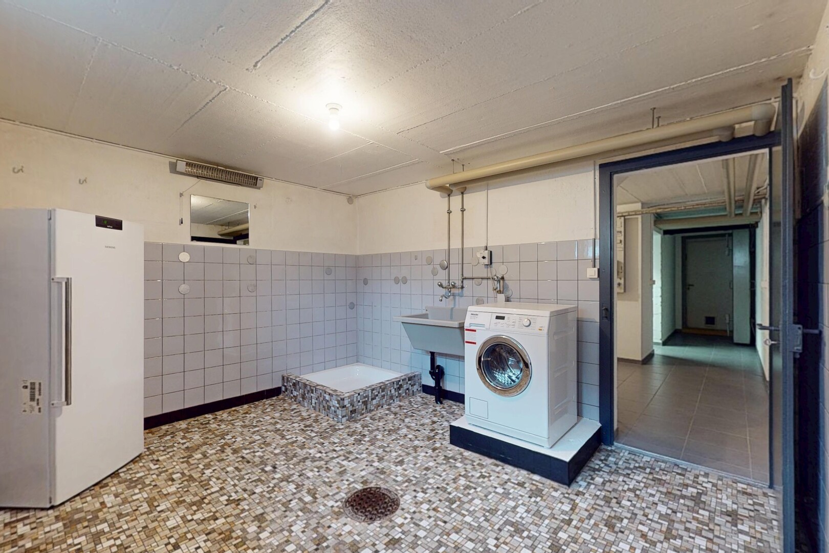 buanderie avec machine à laver / sèche-linge, vasque, buanderie, carrelage, et mur carrelé