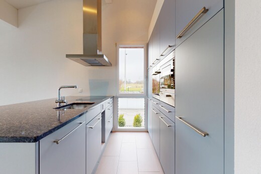kitchen with a center island with sink, wall chimney range hood, dark stone counters, sink, and gray cabinets