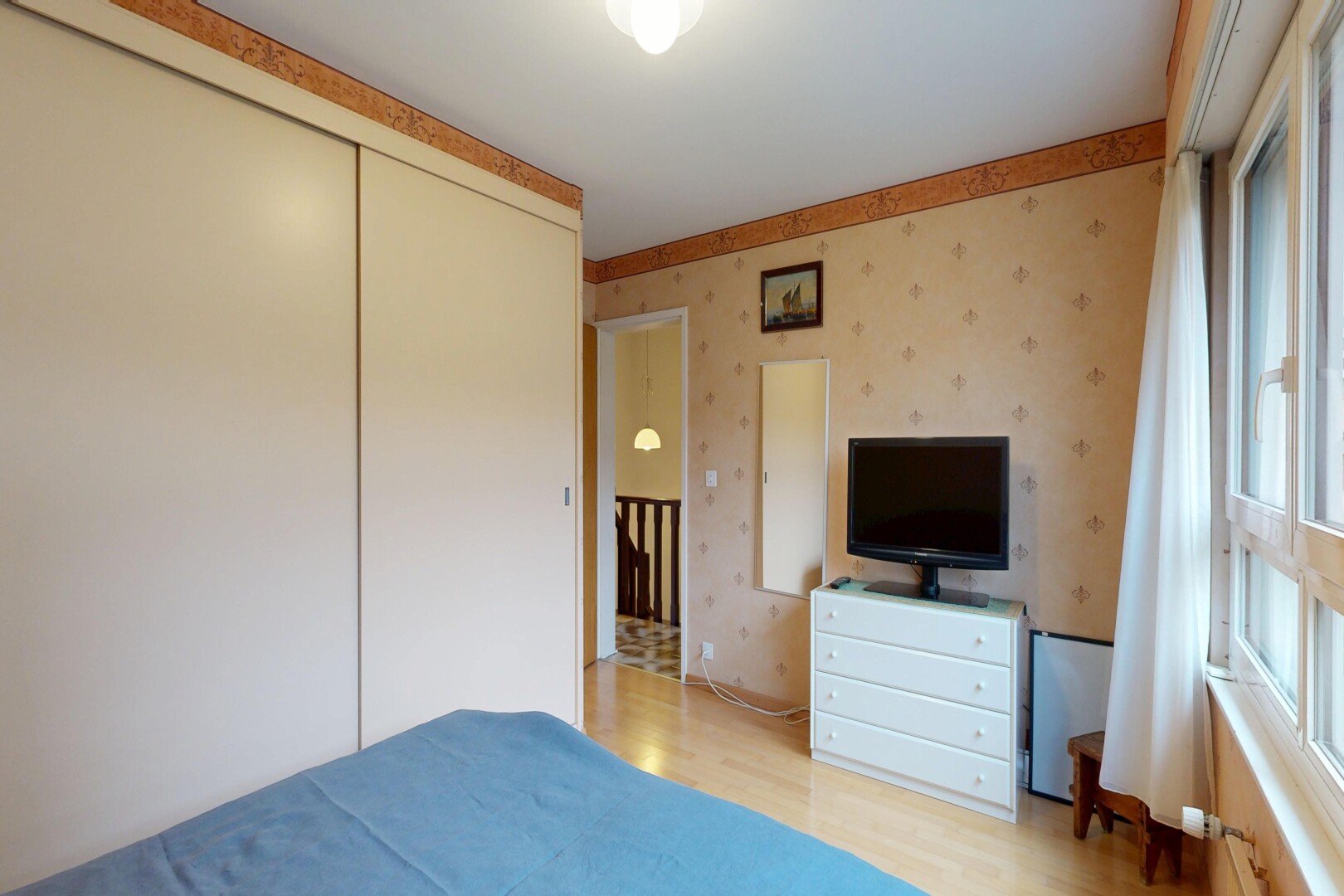 zimmer / schlafzimmer mit wallpaper wall, tapetenwand, fernseher, inside property, und wood finish floor