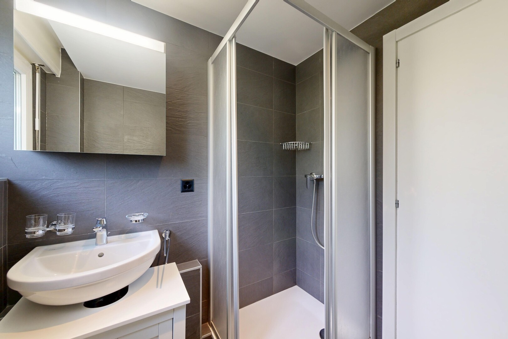 salle de bains avec inside property, tile shower, miroir, lavabo (ou coiffeuse selon le contexte), et douche