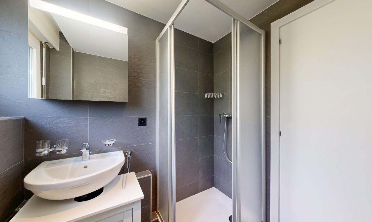salle de bains avec inside property, tile shower, miroir, lavabo (ou coiffeuse selon le contexte), et douche