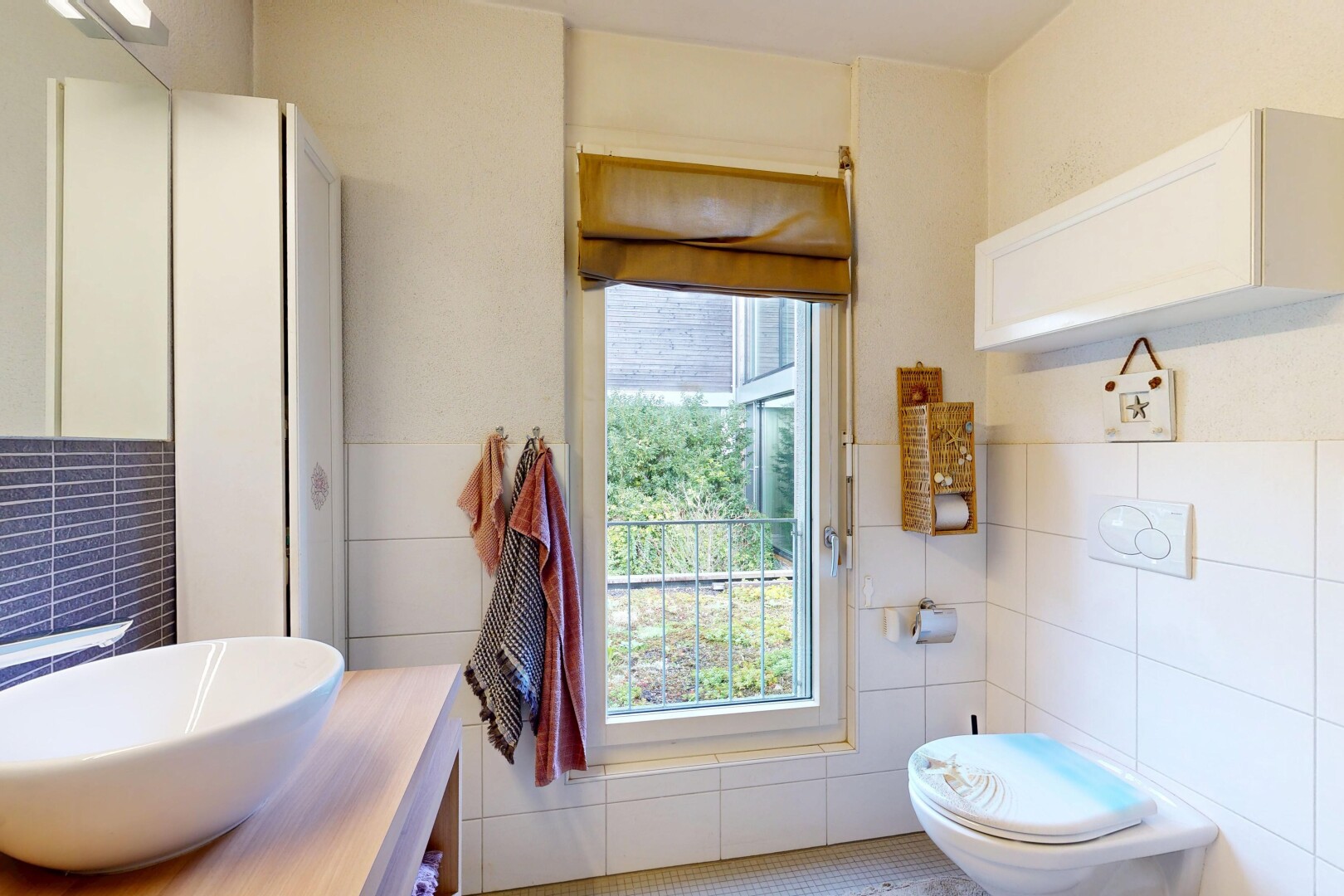 salle de bains avec mur en carrelage, tile wall, inside property, évier, et lumière naturelle