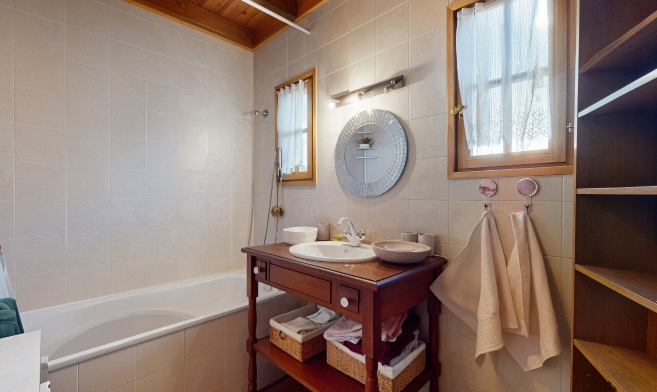 salle de bains avec plafond de bois, miroir, mur carrelé, et vasque