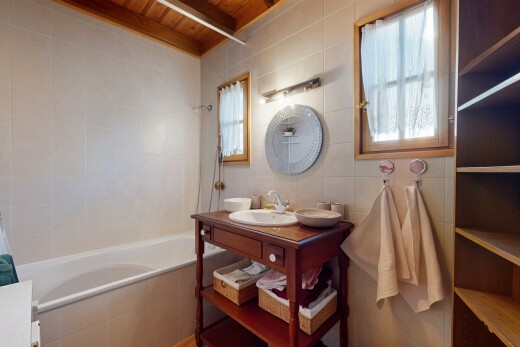salle de bains avec plafond de bois, miroir, mur carrelé, et vasque