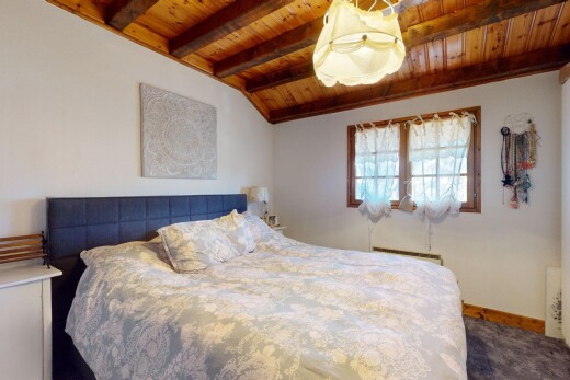 chambre avec plafond voûté, moquette, plafond de bois, lumière naturelle, et poutres apparentes