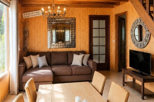salon / salle à manger avec mur en bois, wood wall, lustre remarquable, télévision, et plafond à poutres