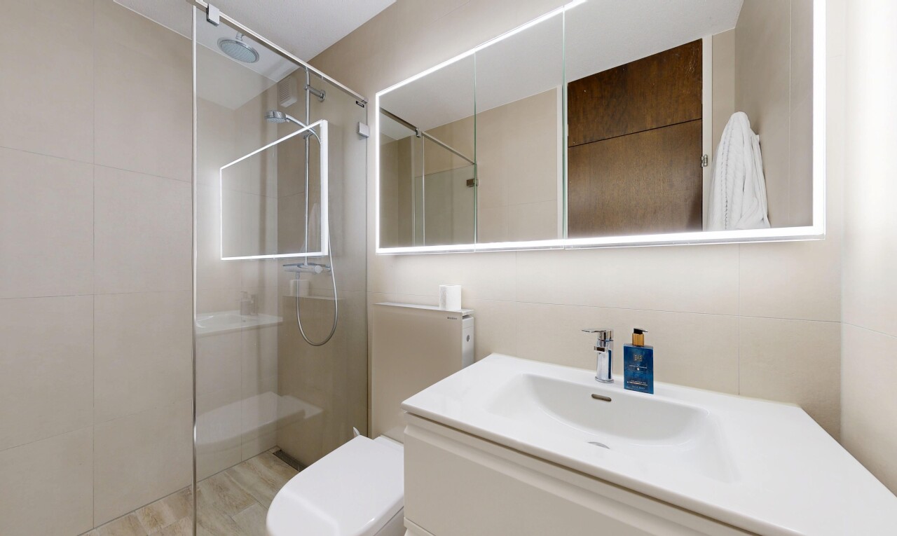 full bath featuring a walk in shower, vanity, and light wood finished floors