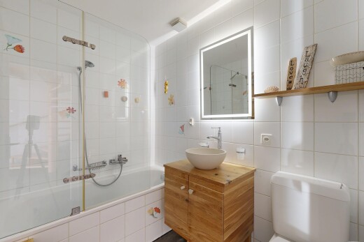 salle de bains avec miroir, douche-bain combinés, salle de bain complète, lavabo (ou coiffeuse selon le contexte), et mur en carrelage