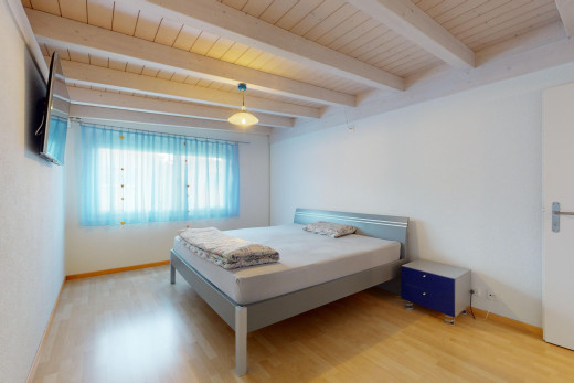 zimmer / schlafzimmer mit natürliches licht, parkettboden, fernseher, und balkendecke