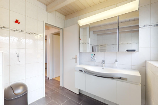 bad mit fliesenwand, spiegel, und balkendecke