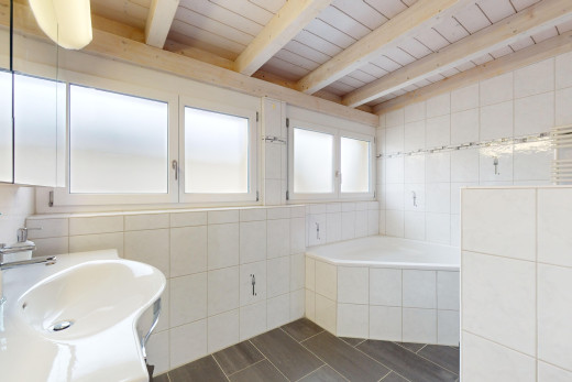 bad mit fliesenwand und balkendecke