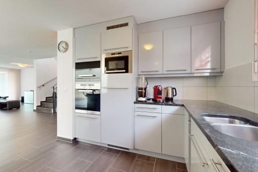 küche mit ofen, küchenrückwand beim herd, weiße schränke, lüftungsgitter, und parkettboden