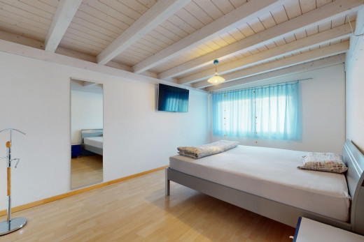 zimmer / schlafzimmer mit natürliches licht, parkettboden, fernseher, und balkendecke