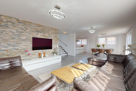 wohnzimmer mit fliesenboden, treppen, fernseher, steinwand, und natürliches licht