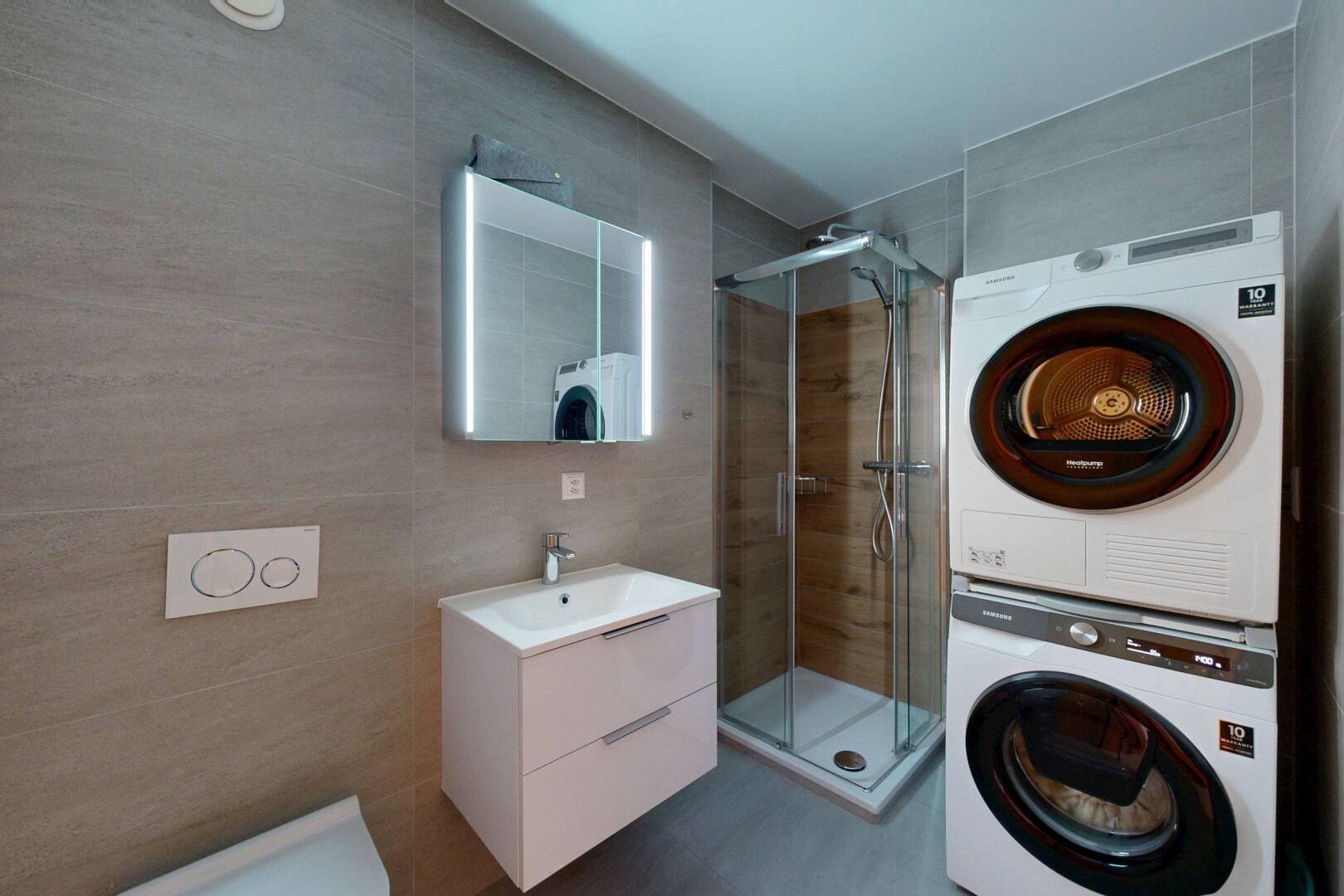 bathroom featuring tile walls, a stall shower, stacked washing machine and dryer, and vanity