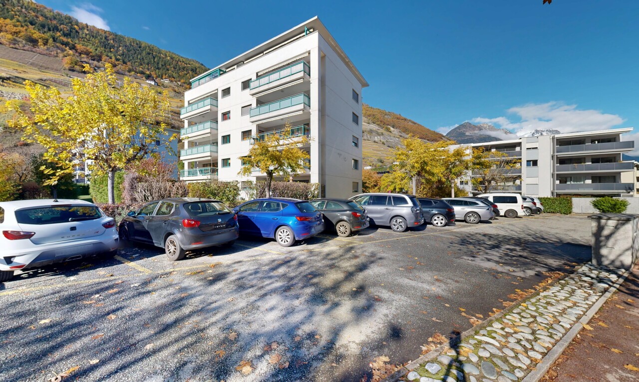 view of apartment building / complex with a mountain view and uncovered parking