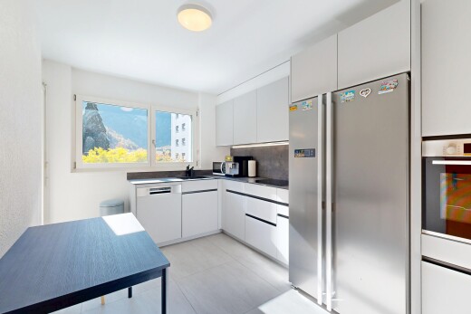 cuisine avec réfrigérateur, armoires blanches, plans de travail, four, et natural light