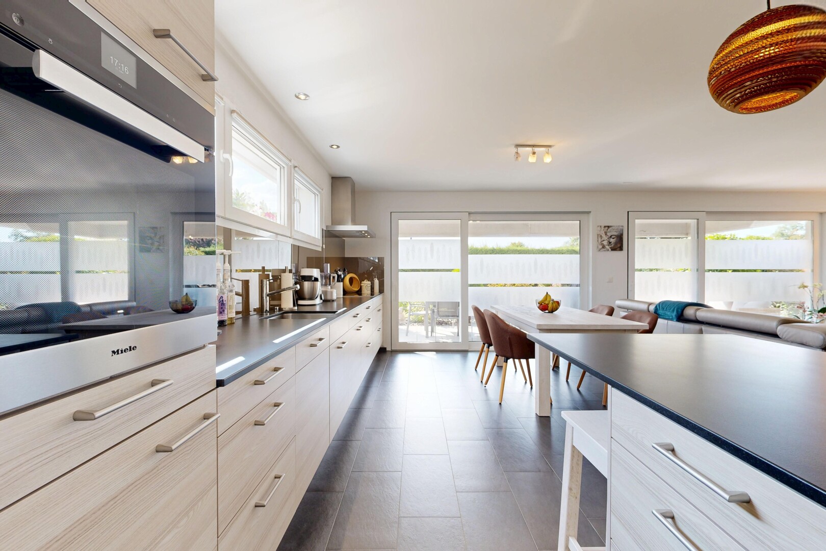 cuisine avec four, dark countertops, plans de travail, dark floor, et light brown cabinets