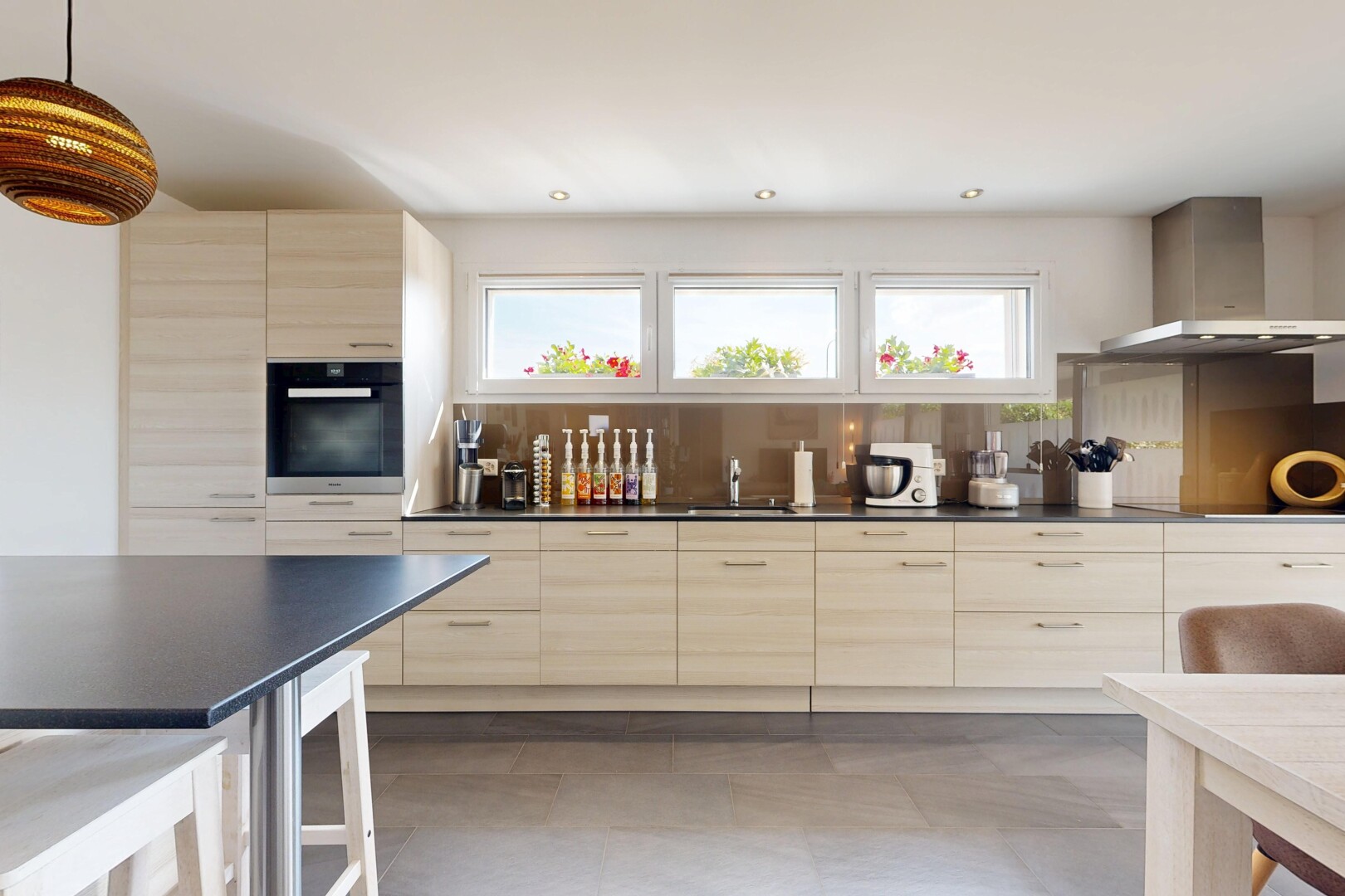 cuisine avec plans de travail, dark countertops, hotte, armoires marron clair, et light brown cabinets