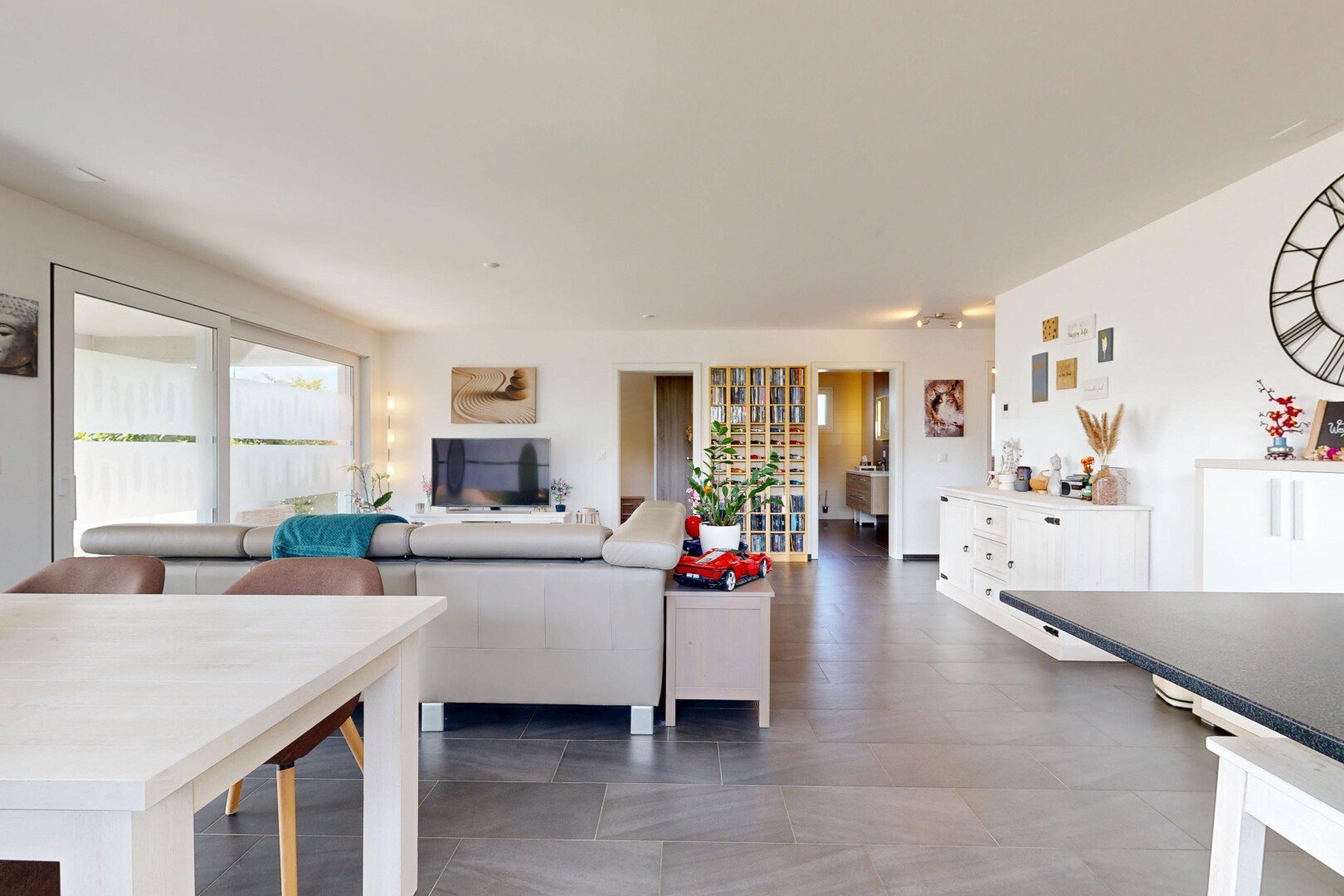 salon / salle à manger avec éclairage sur rail, drywall, cloison sèche, et télévision