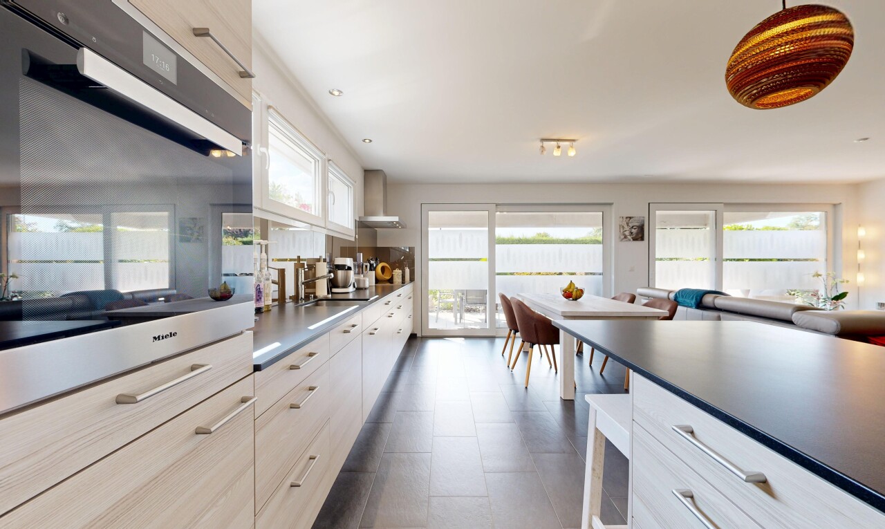 cuisine avec four, dark countertops, plans de travail, dark floor, et light brown cabinets