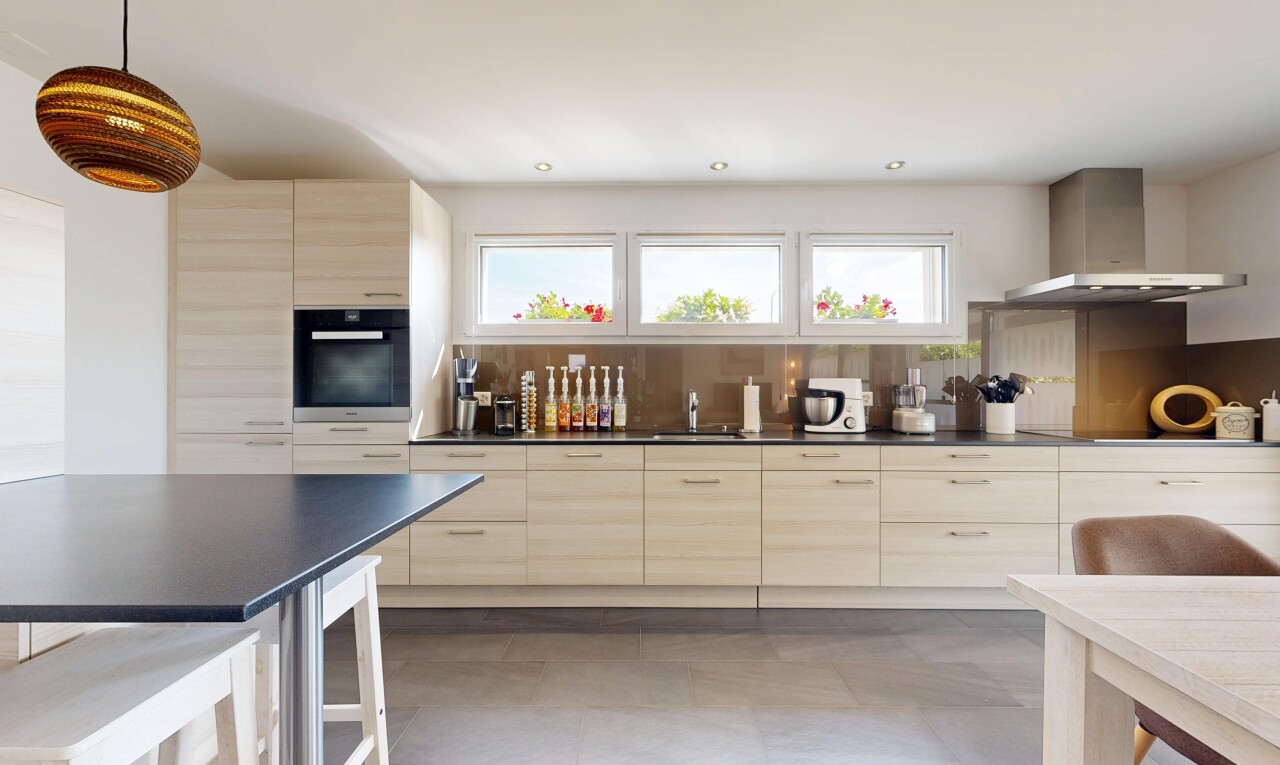 cuisine avec plans de travail, dark countertops, hotte, armoires marron clair, et light brown cabinets
