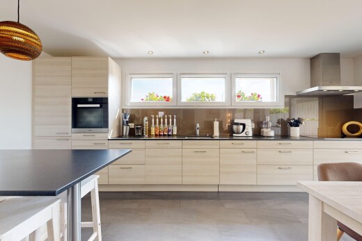 cuisine avec plans de travail, dark countertops, hotte, armoires marron clair, et light brown cabinets
