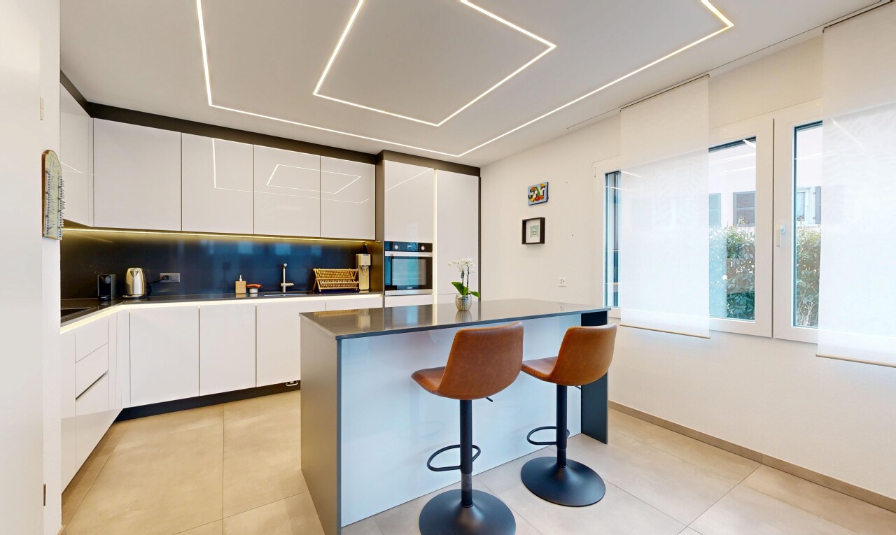 kitchen featuring modern cabinets, a kitchen breakfast bar, white cabinets, and backsplash