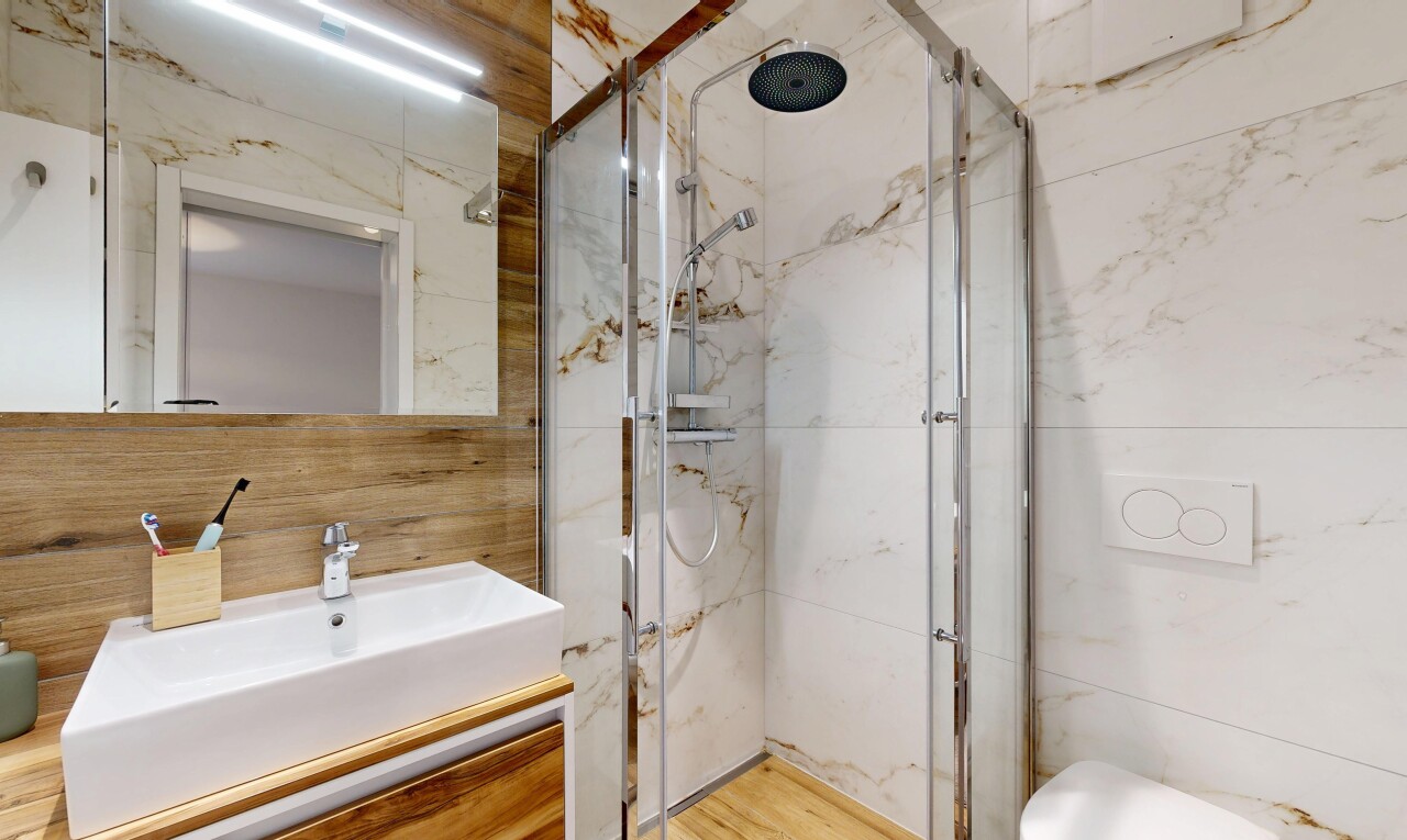 bathroom with vanity and a marble finish shower
