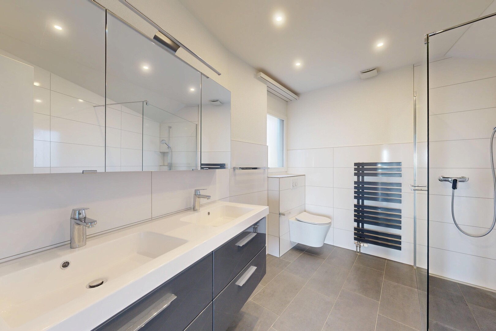 salle de bains avec douche, salle de bain complète, chauffe-serviettes, double vasque, et inside property