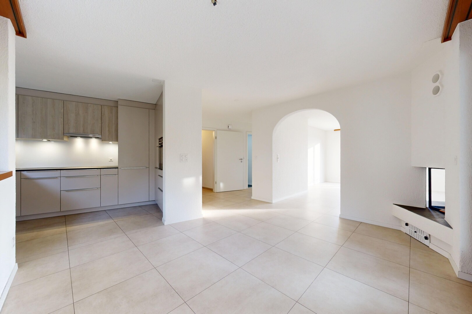 pièce vide avec light floor, passages en arc, cloison sèche, drywall, et sol en carrelage