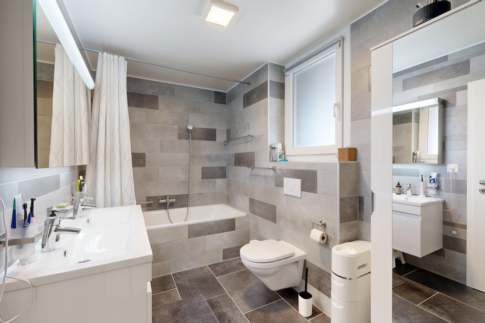 salle de bains avec miroir, lavabo (ou coiffeuse selon le contexte), mur en carrelage, tile wall, et salle de bain complète