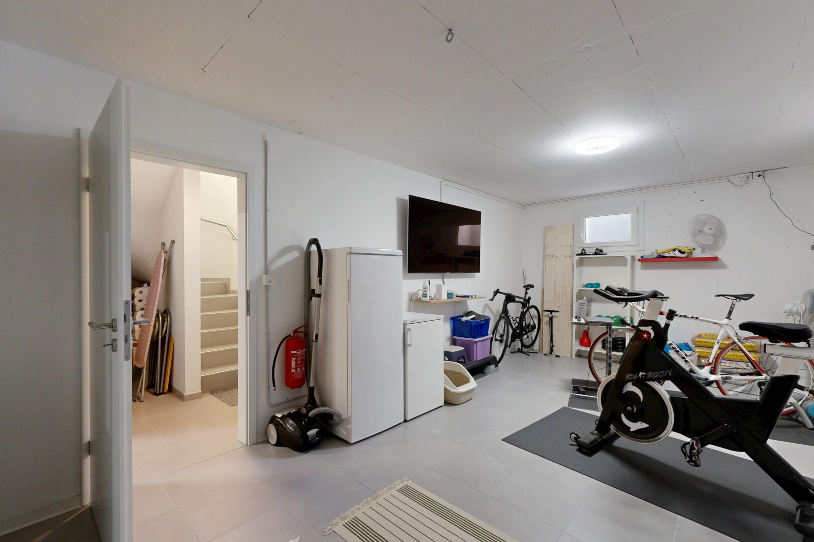 gym avec cloison sèche, drywall, télévision, et sous-sol