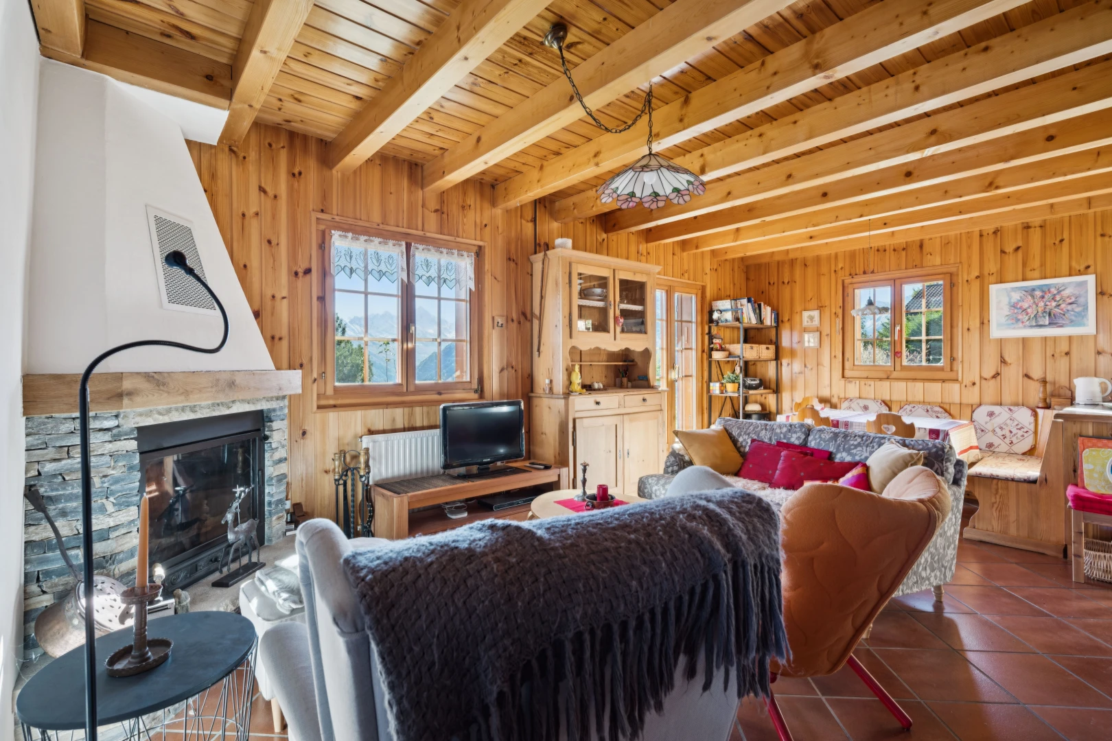 living area with a stone fireplace, a wood ceiling with exposed beams, dark tile patterned floors, and wood walls