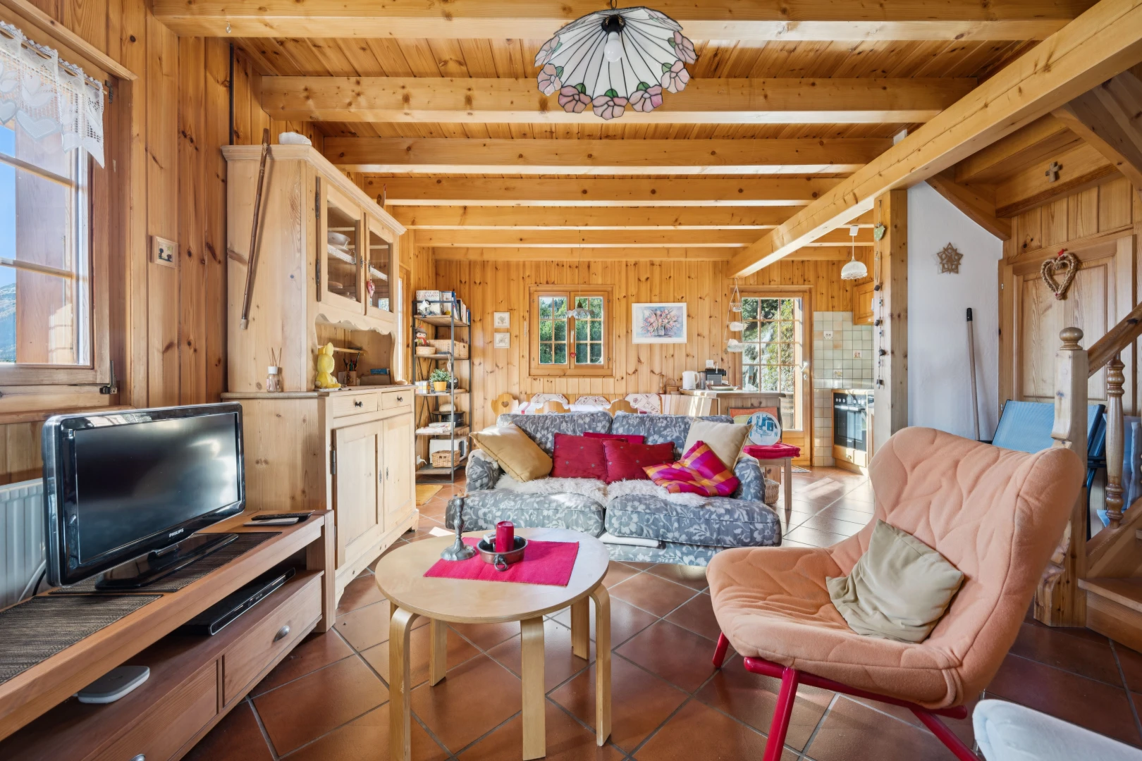 living room featuring wooden walls, hanging light fixtures, a wood ceiling with exposed beams, and dark tile patterned flooring