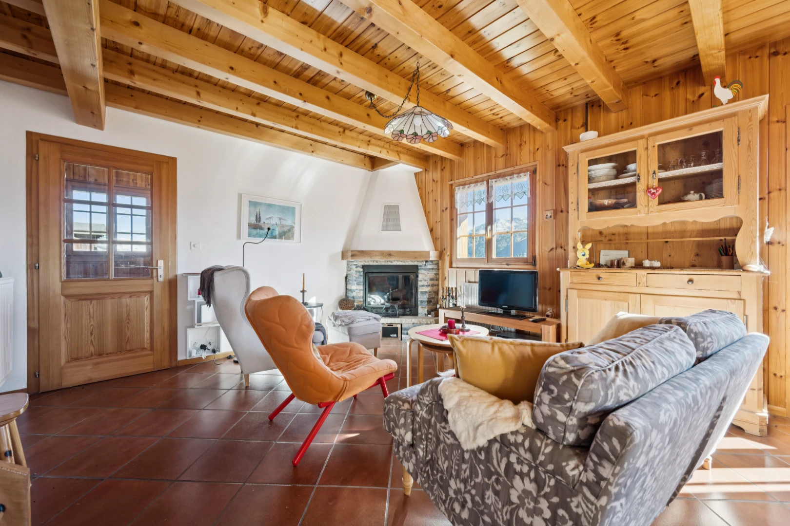 living room with a stone fireplace, a wooden ceiling with exposed beams, dark tile patterned flooring, and wooden walls