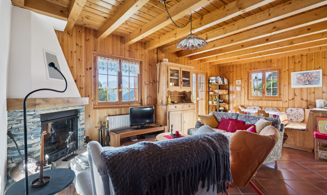living area with a stone fireplace, a wood ceiling with exposed beams, dark tile patterned floors, and wood walls