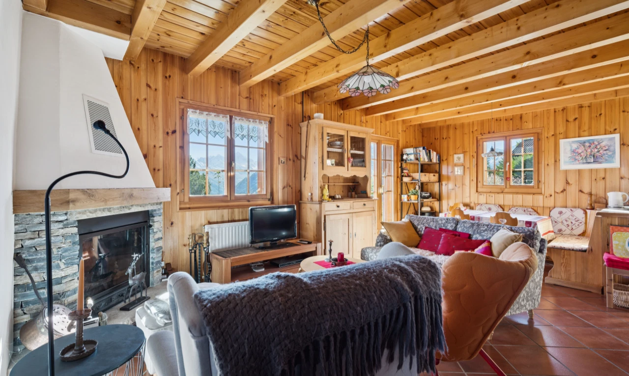 living area with a stone fireplace, a wood ceiling with exposed beams, dark tile patterned floors, and wood walls