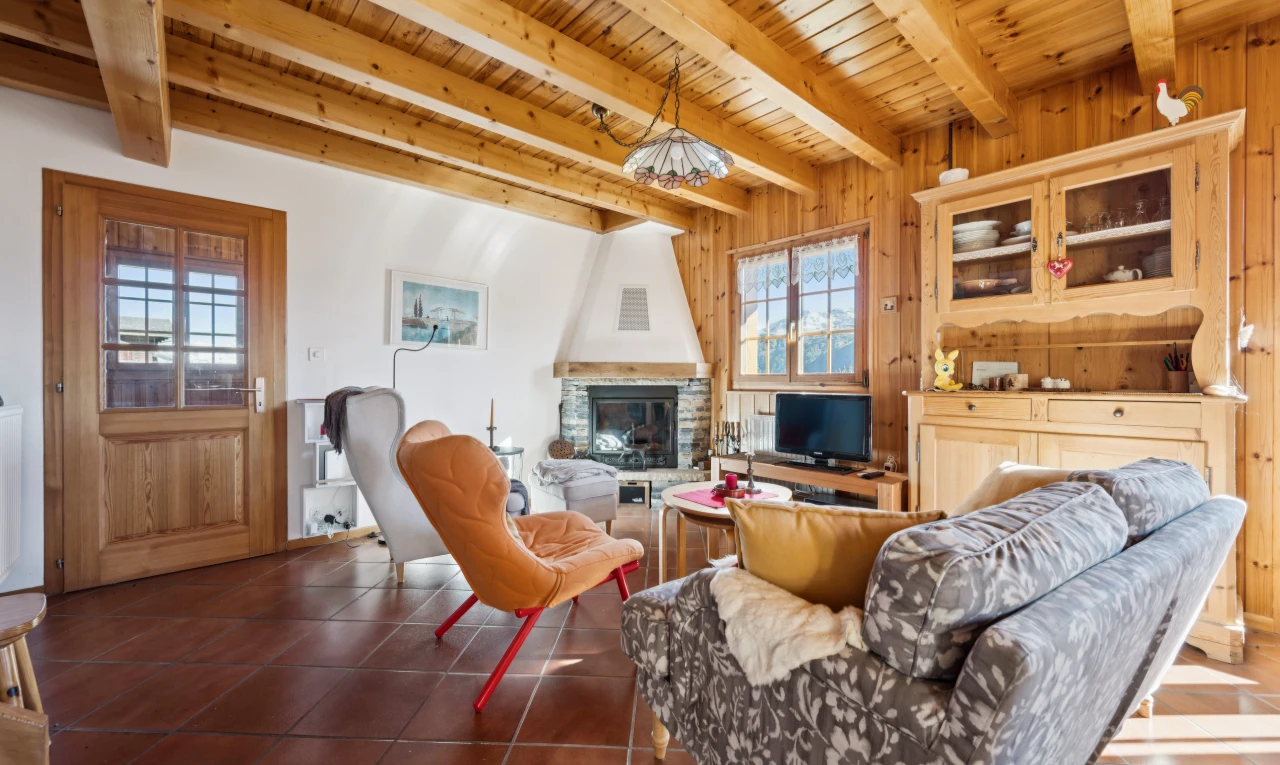 living room with a stone fireplace, a wooden ceiling with exposed beams, dark tile patterned flooring, and wooden walls