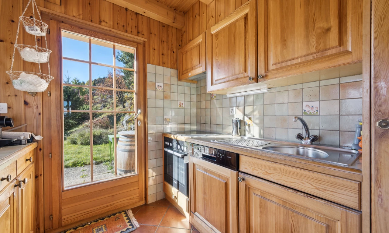 kitchen featuring backsplash, light tile patterned flooring, light countertops, wood finish cabinetry, and beamed ceiling