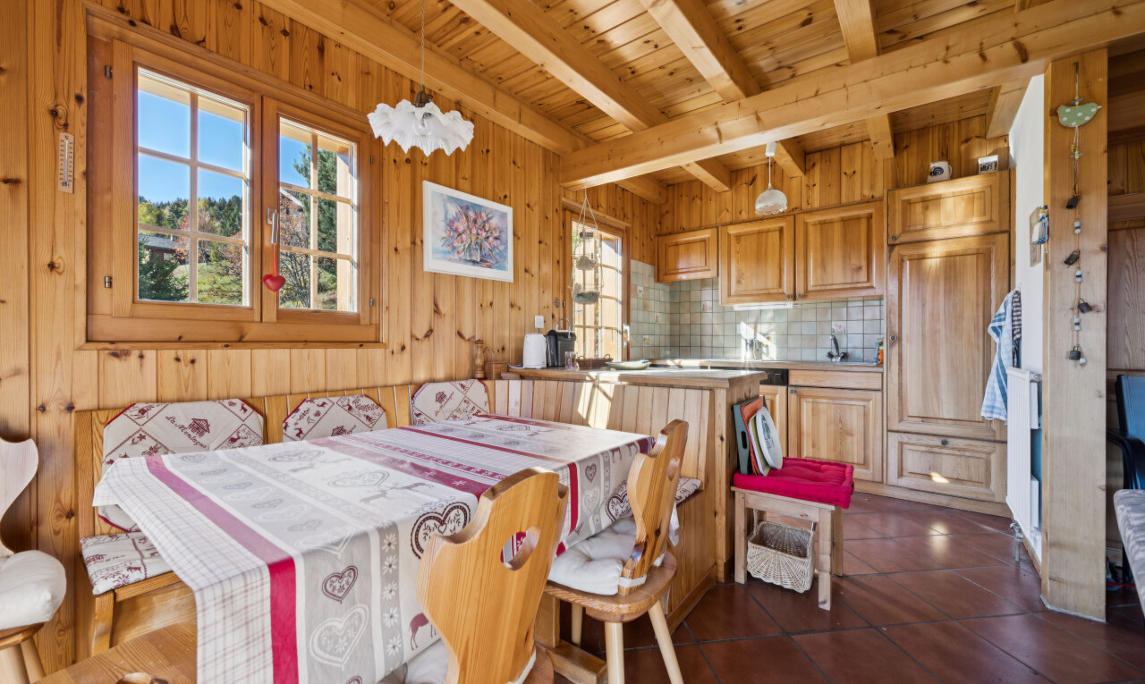 dining space featuring breakfast area, wood walls, a wooden ceiling with exposed beams, and dark tile patterned floors