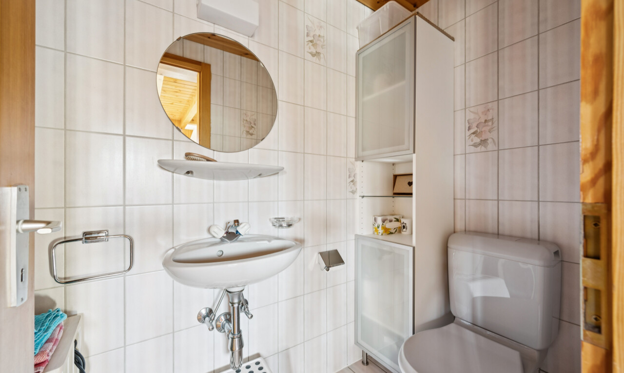 half bath featuring toilet and tile walls