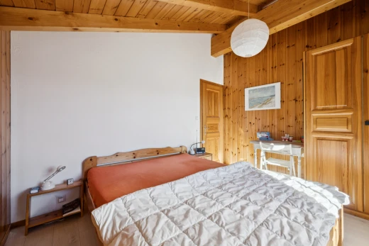 room featuring wooden walls, vaulted ceiling with beams, wood ceiling, hanging light fixtures, and light wood-type flooring