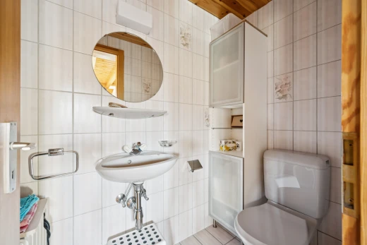 half bath featuring toilet and tile walls
