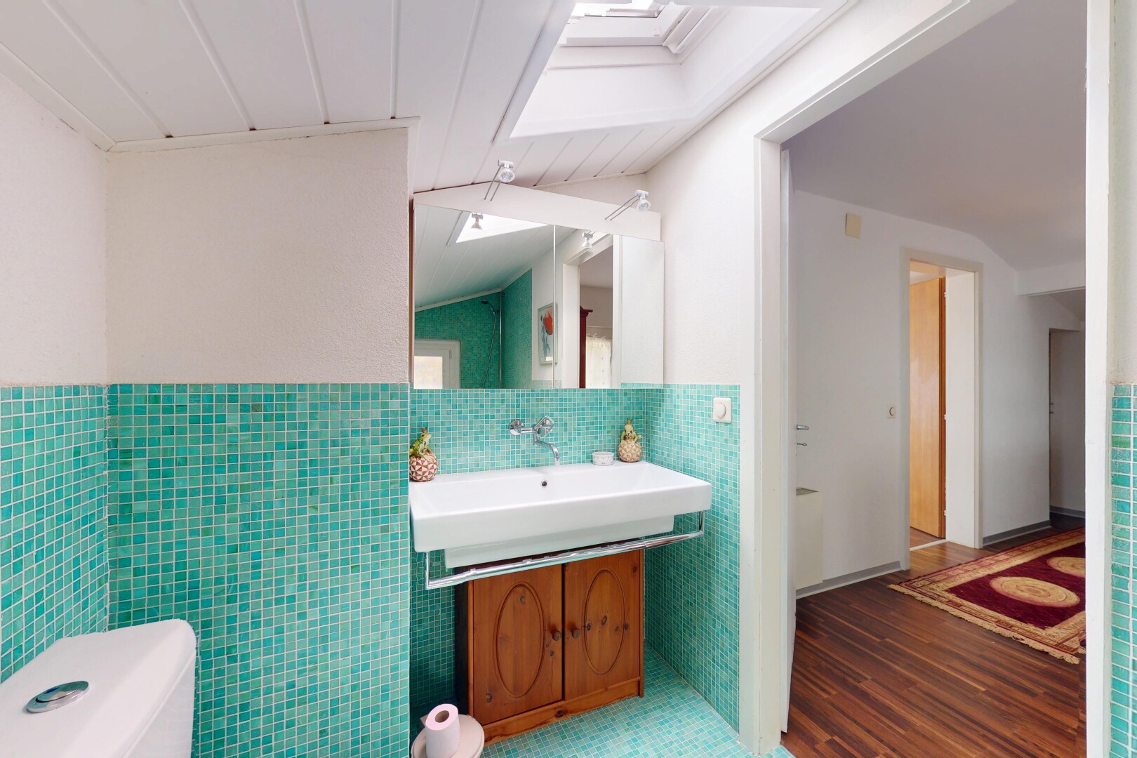 salle de bains avec miroir, toilette, et mur en carrelage