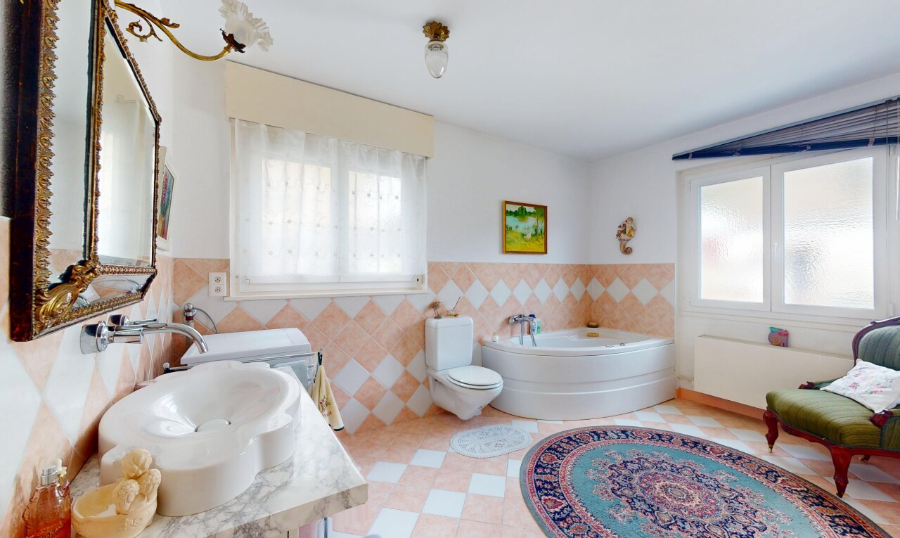 salle de bains avec évier, lumière naturelle, mur en carrelage, et bain