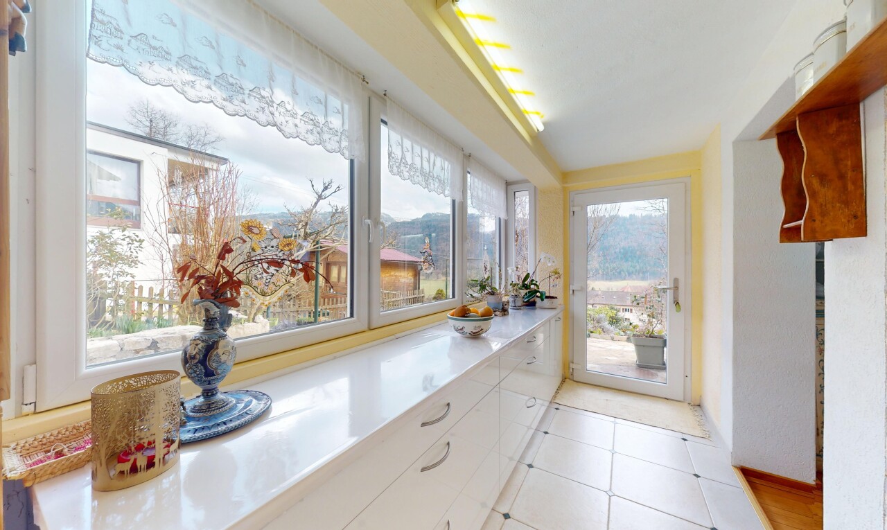 cuisine avec plans de travail, lumière naturelle, sol en carrelage, et armoires blanches
