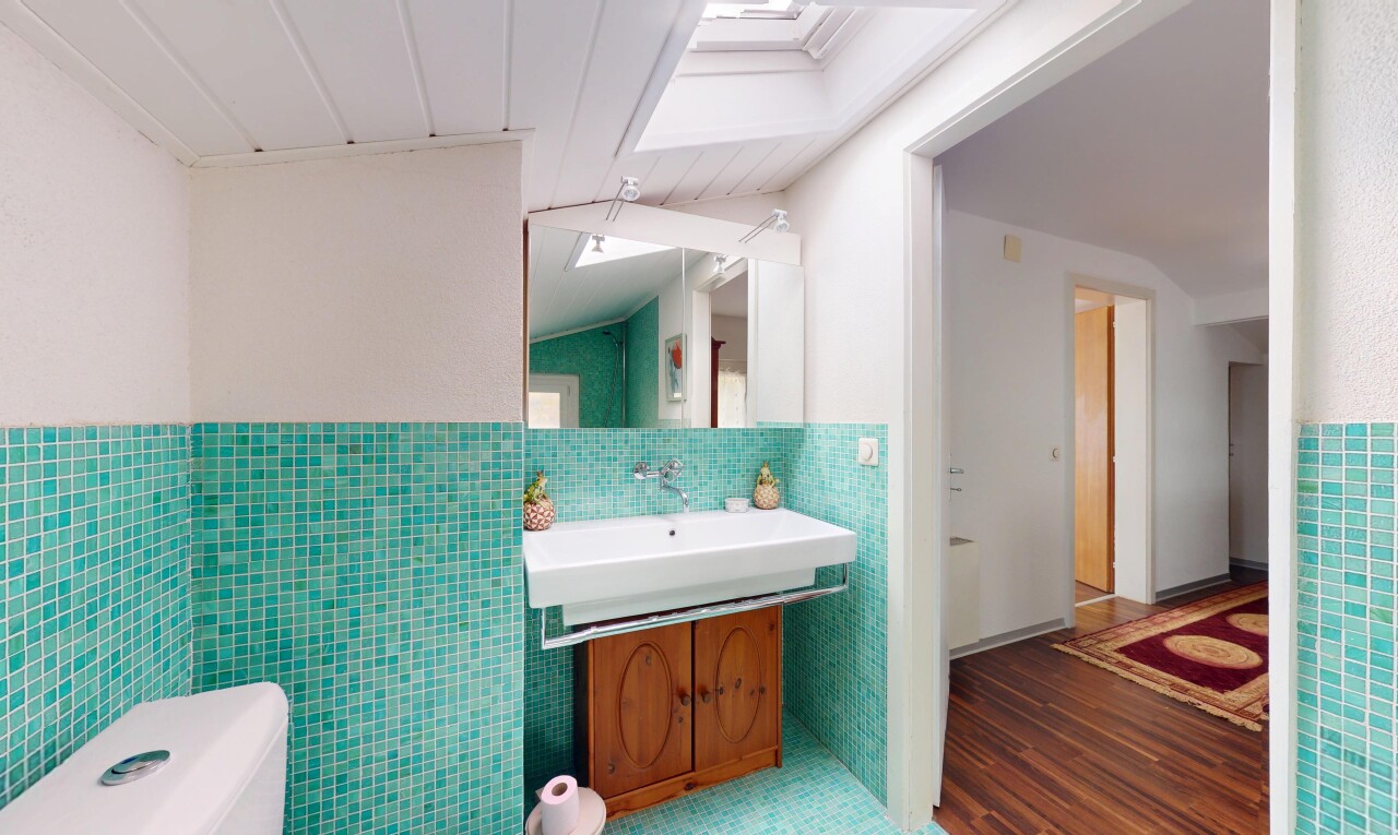 salle de bains avec miroir, toilette, et mur en carrelage