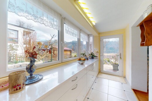 cuisine avec plans de travail, lumière naturelle, sol en carrelage, et armoires blanches